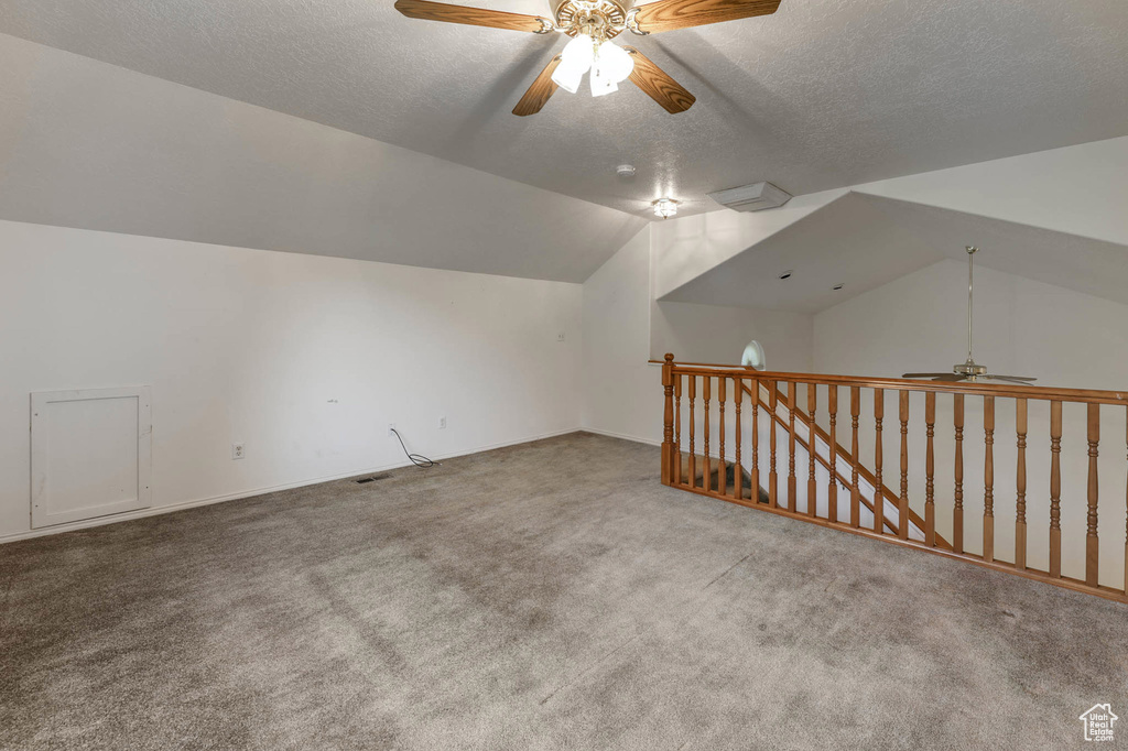 Additional living space featuring a ceiling fan, carpet flooring, a textured ceiling, and vaulted ceiling