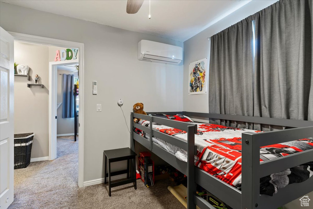 Bedroom with a wall unit AC, carpet flooring, baseboards, and ceiling fan