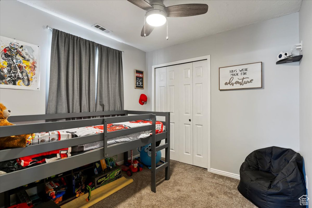 Carpeted bedroom with a closet, baseboards, and ceiling fan