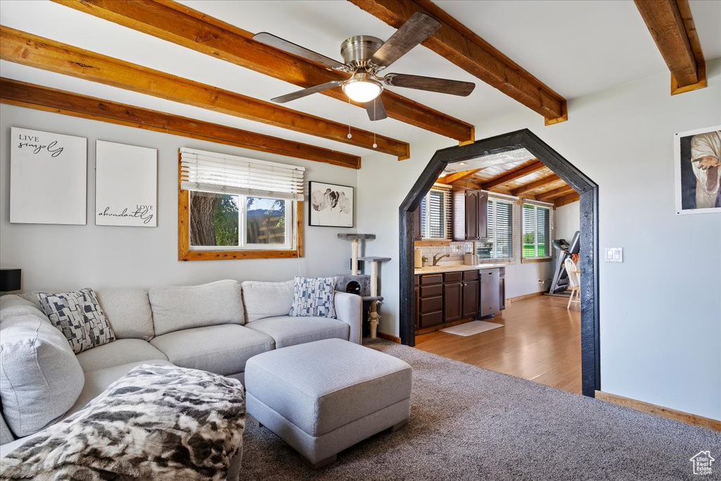 Living room with beamed ceiling, light wood-style floors, and ceiling fan