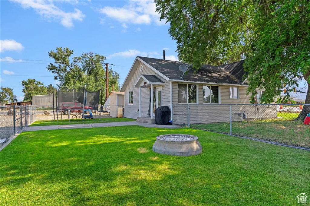 Rear view of house featuring a trampoline and an outdoor fire pit