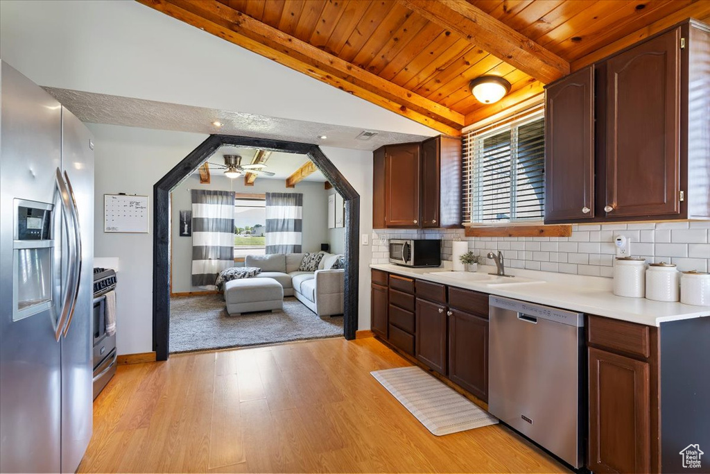 Kitchen with stainless steel appliances, a sink, wood ceiling, light countertops, and tasteful backsplash