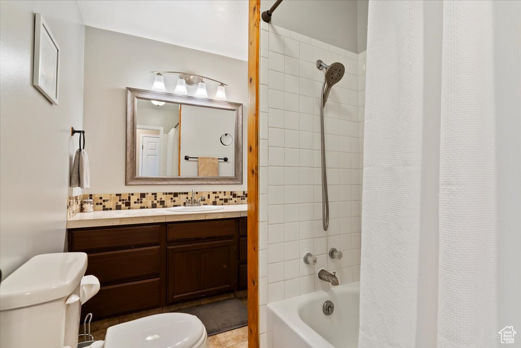 Full bath featuring toilet, vanity, shower / bathtub combination with curtain, and decorative backsplash