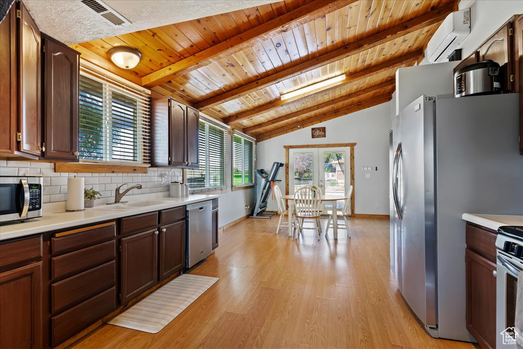 Kitchen featuring stainless steel appliances, a wall unit AC, wood ceiling, light countertops, and a sink