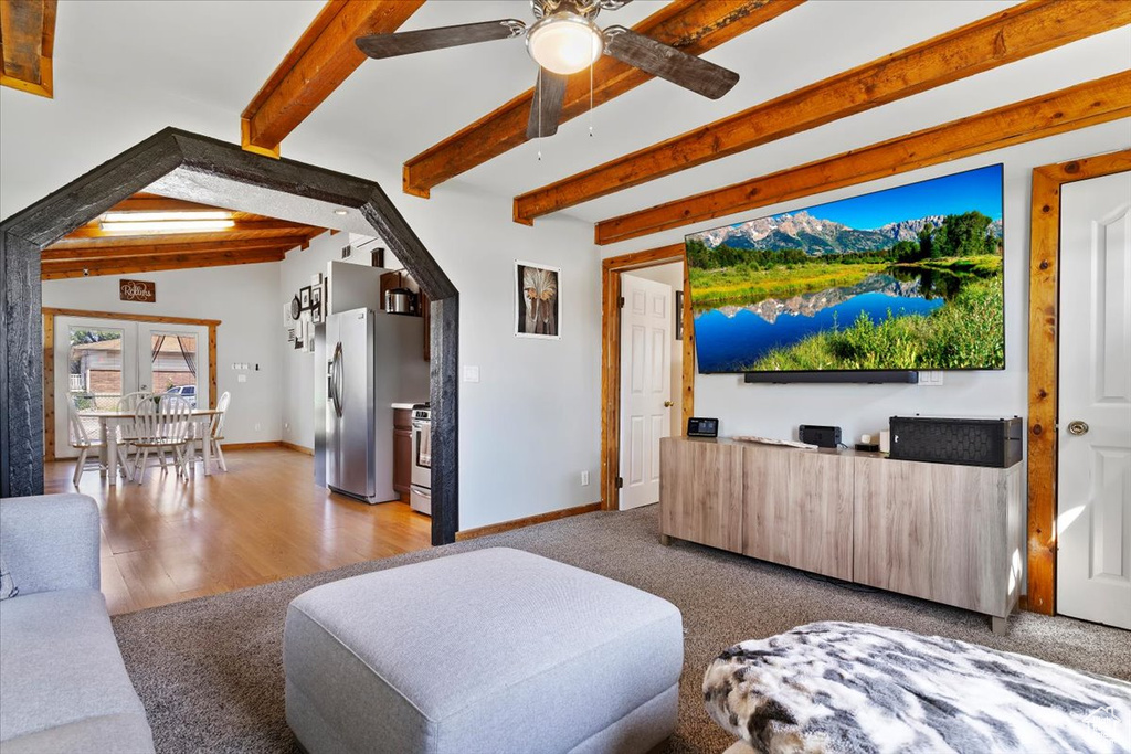 Living room featuring beam ceiling, ceiling fan, baseboards, and wood finished floors