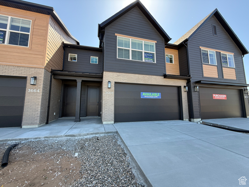 View of property featuring a garage, driveway, and brick siding