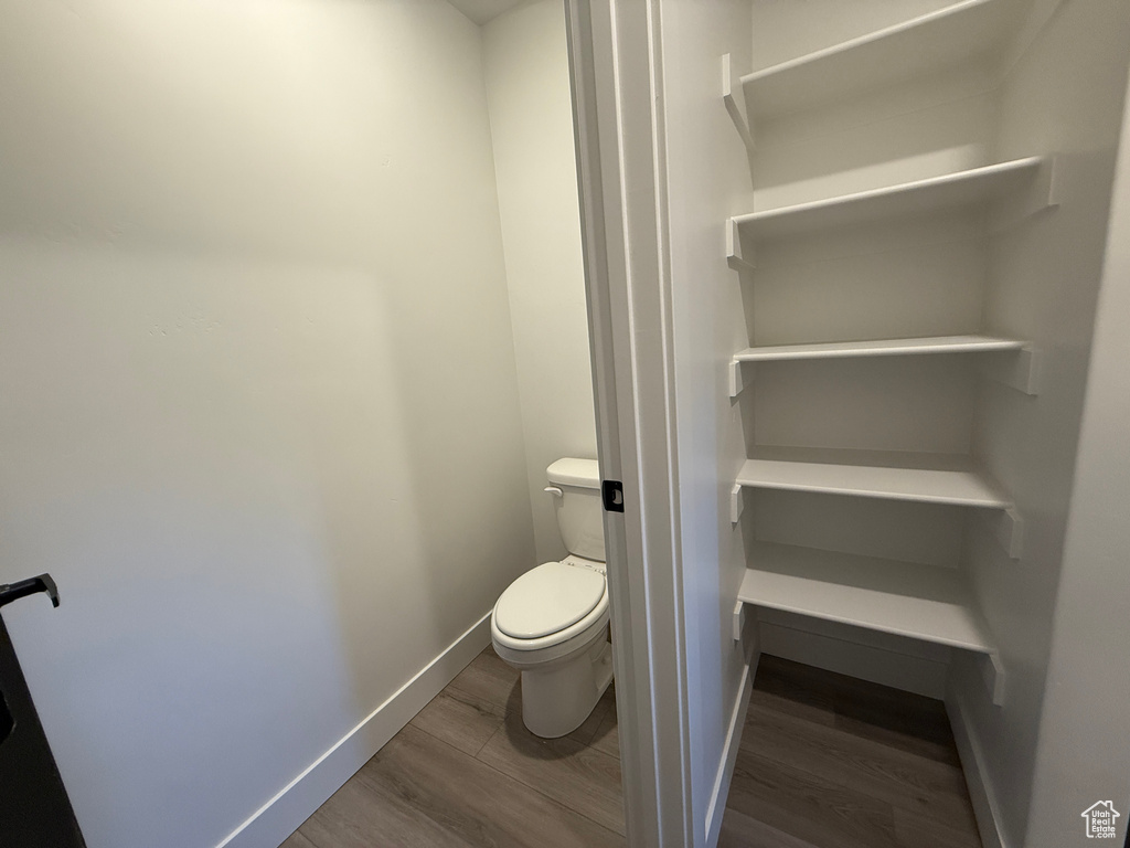 Bathroom featuring wood finished floors, toilet, and baseboards