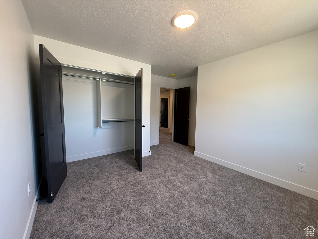 Unfurnished bedroom with a textured ceiling, baseboards, carpet flooring, and a closet