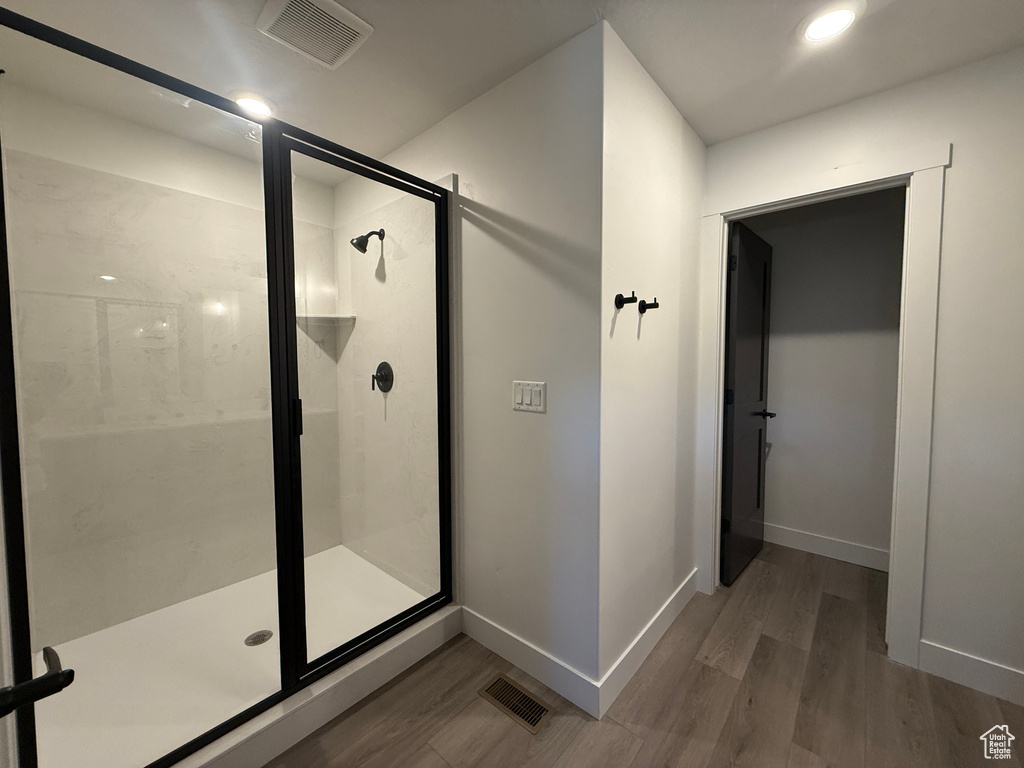 Full bath with wood finished floors, a shower stall, and baseboards