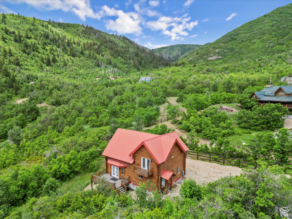 Aerial view of property and surrounding area with a heavily wooded area and a mountainous background
