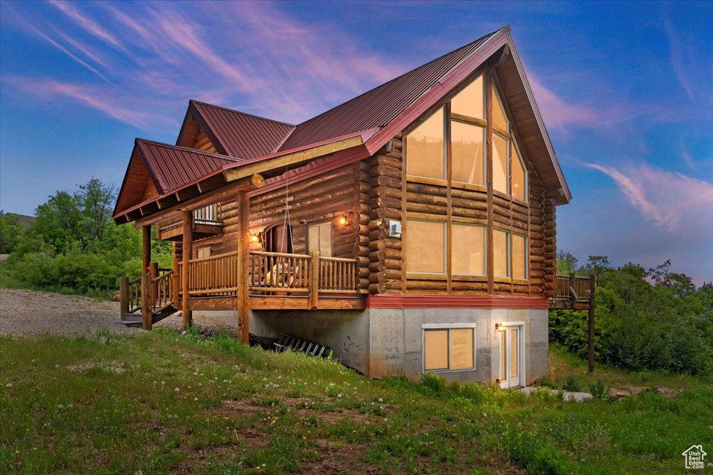 Property exterior at dusk featuring log exterior, a deck, and metal roof