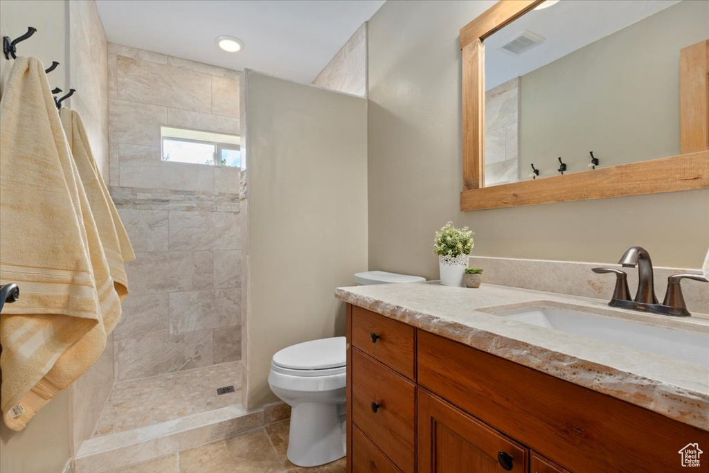 Full bathroom featuring toilet, vanity, a walk in shower, and recessed lighting