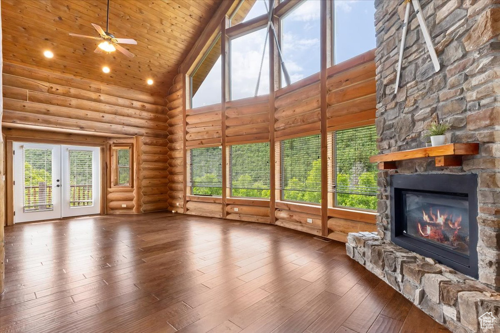 Unfurnished living room with high vaulted ceiling, a stone fireplace, a ceiling fan, log walls, and wood ceiling
