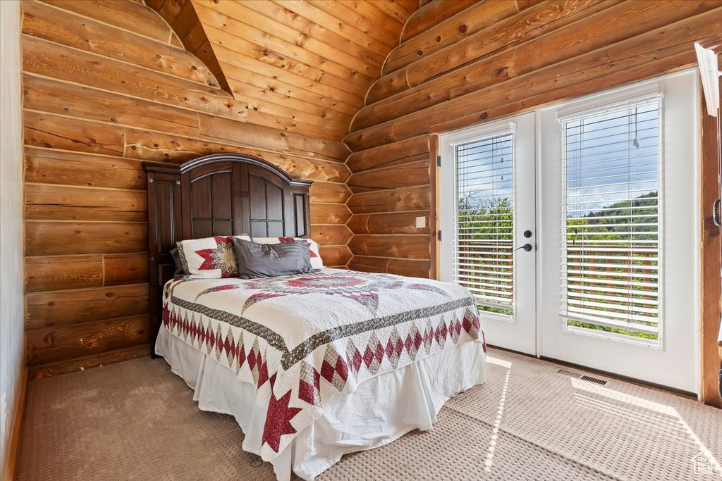 Bedroom with log walls, access to exterior, and light carpet