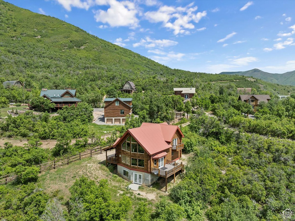 Aerial view of property and surrounding area with a heavily wooded area and a mountain backdrop