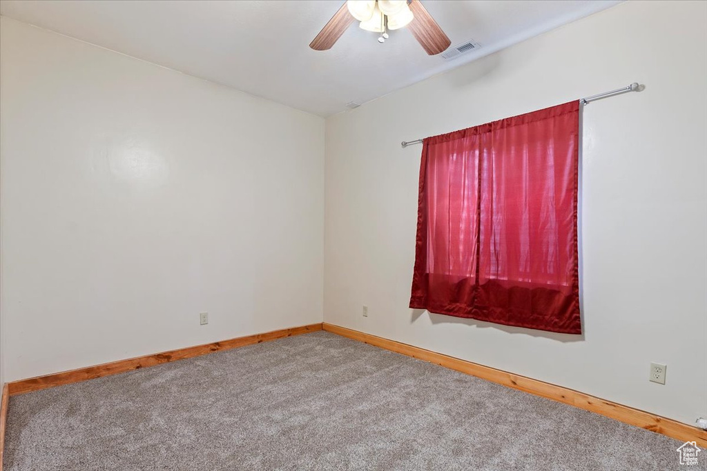 Carpeted spare room with ceiling fan and baseboards