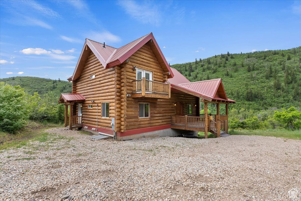 View of side of home with a view of trees, log siding, and metal roof