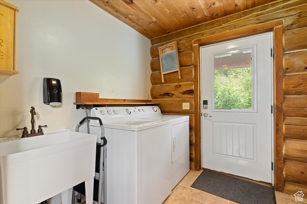 Laundry area with washing machine and dryer, log walls, wood ceiling, and cabinet space