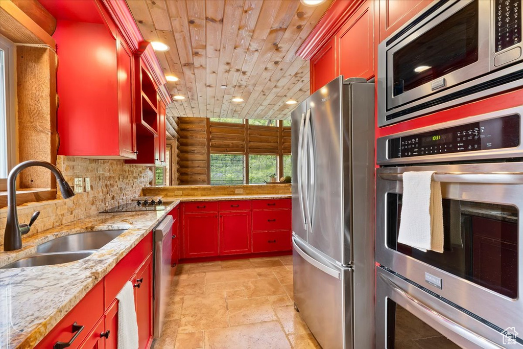 Kitchen with stainless steel appliances, a sink, wooden ceiling, stone tile flooring, and recessed lighting