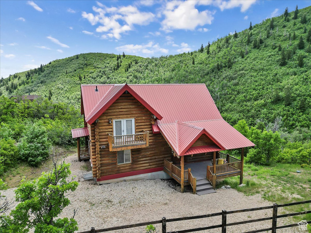Log cabin with a wooded view, log siding, a deck with mountain view, metal roof, and french doors