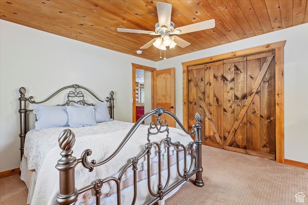Carpeted bedroom with baseboards, wood ceiling, and ceiling fan