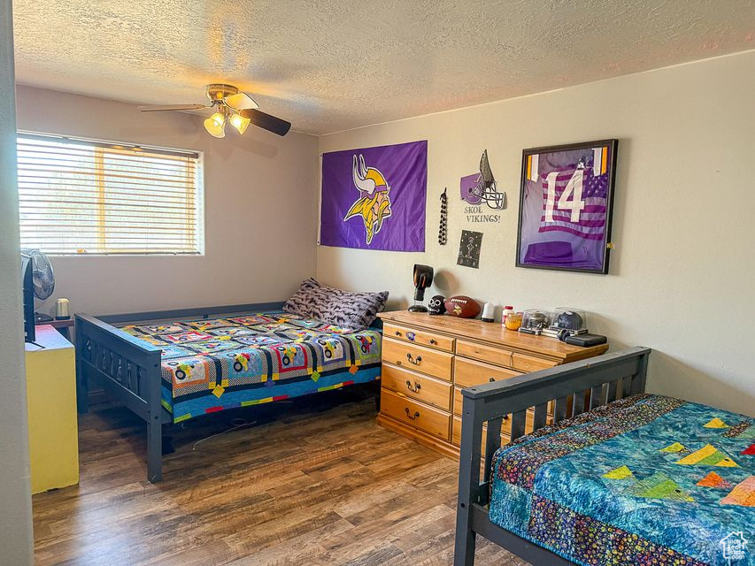 Bedroom with wood finished floors, a textured ceiling, and ceiling fan