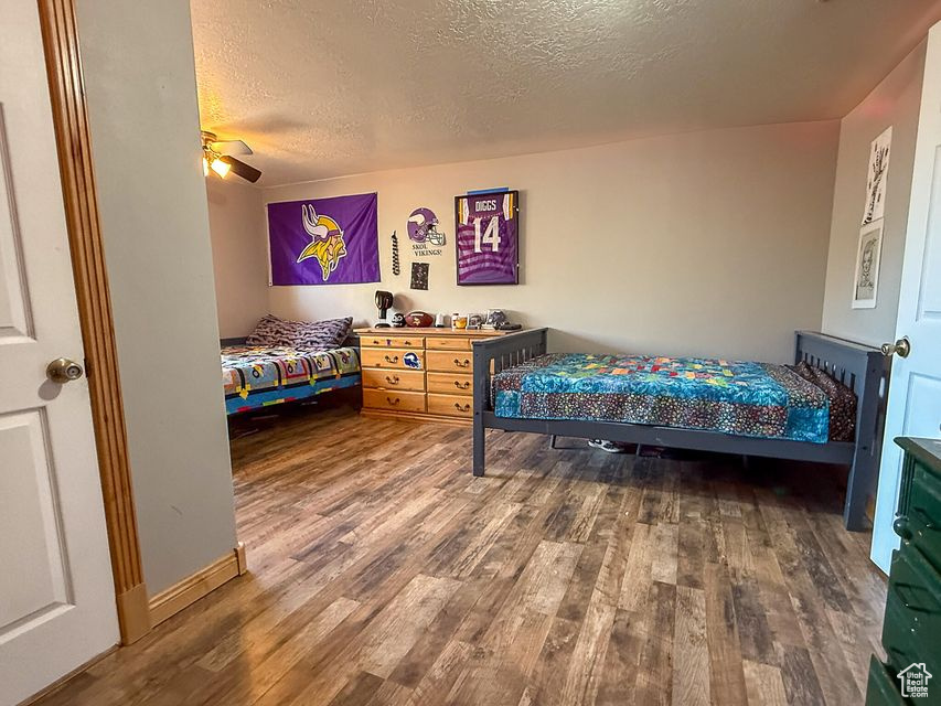 Bedroom featuring wood finished floors, a textured ceiling, and ceiling fan