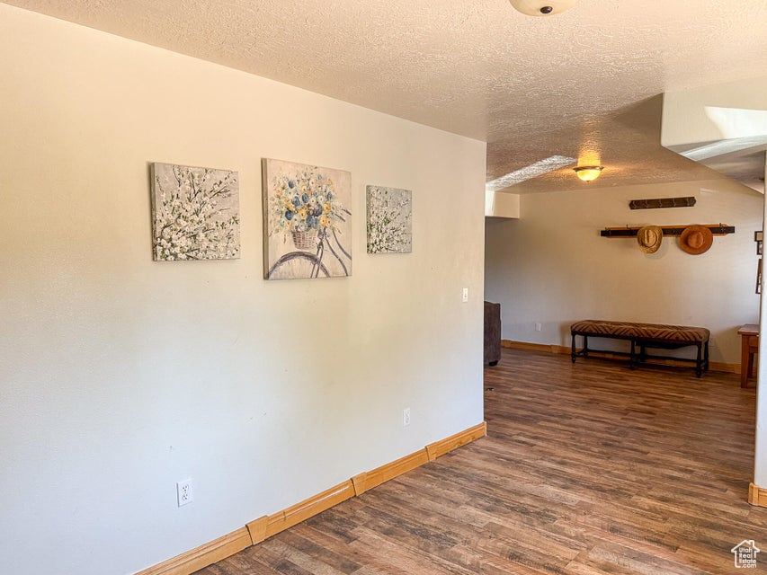 Unfurnished room with a textured ceiling, wood finished floors, and baseboards
