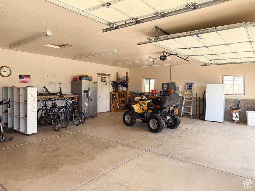 Garage with stainless steel fridge and a garage door opener