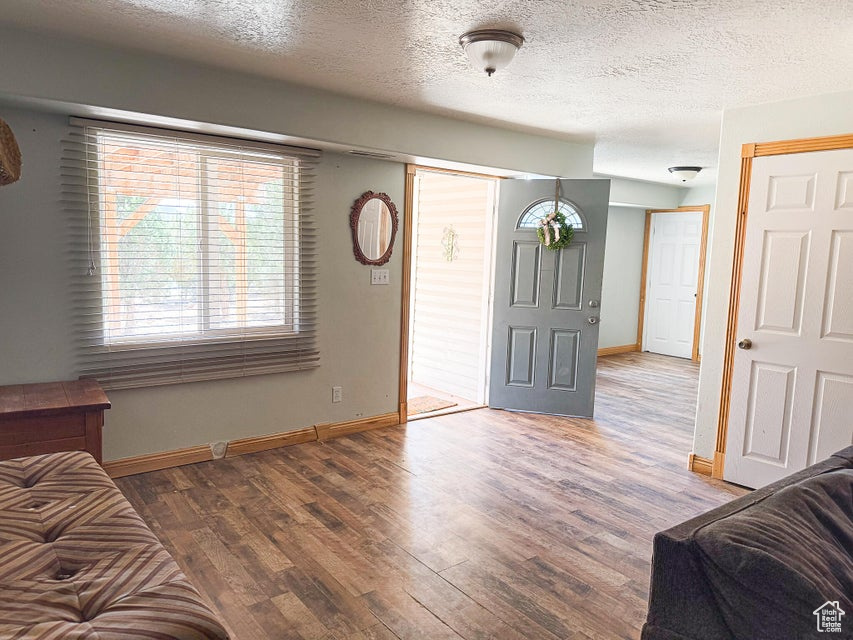 Entrance foyer featuring baseboards, wood finished floors, and a textured ceiling