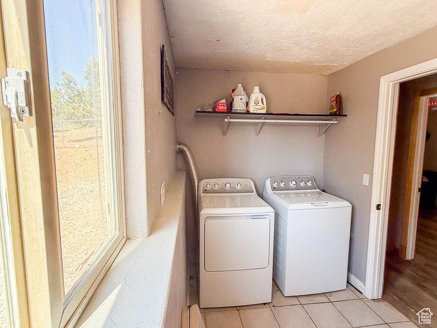 Washroom with washing machine and clothes dryer, light tile patterned floors, and a textured ceiling