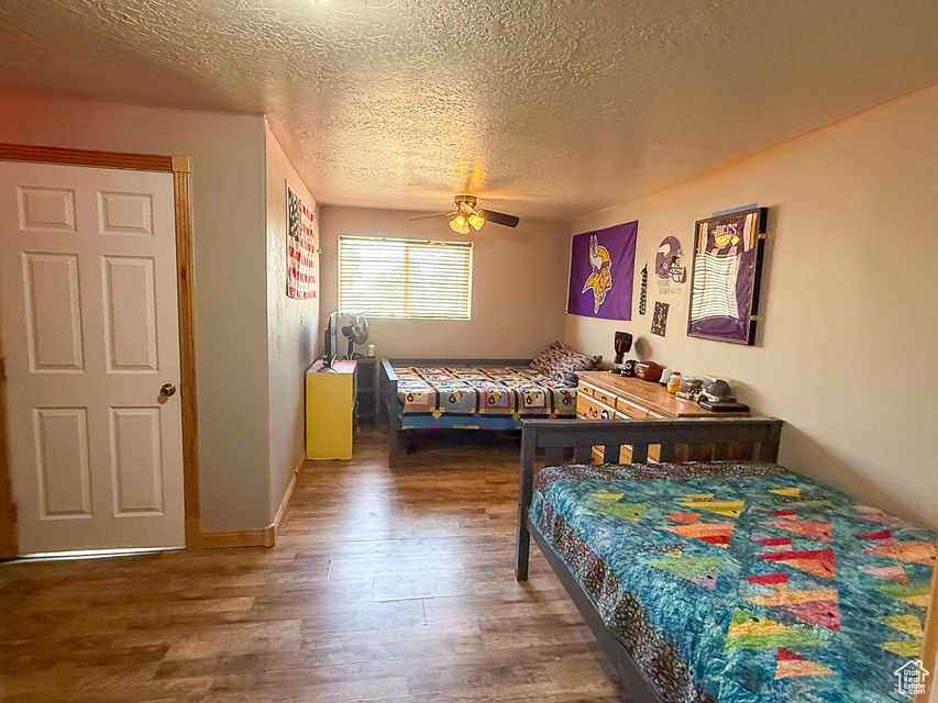 Bedroom featuring wood finished floors, a textured ceiling, and a ceiling fan