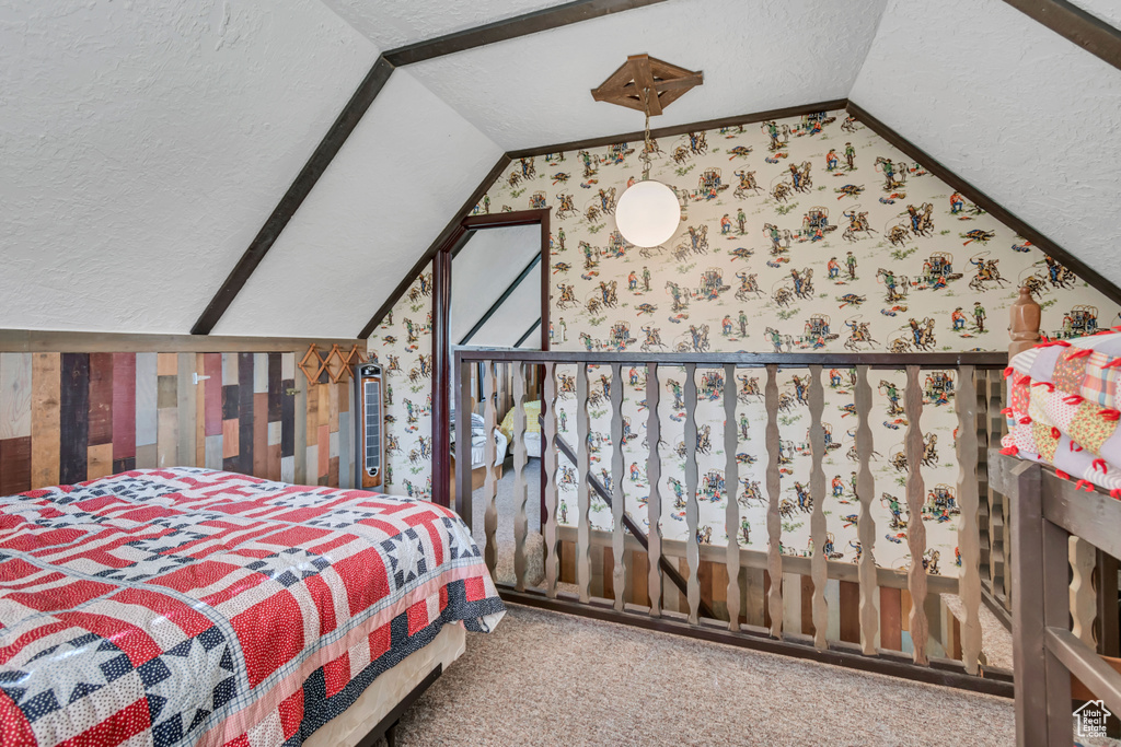 Carpeted bedroom with vaulted ceiling, wallpapered walls, a textured ceiling, and multiple windows