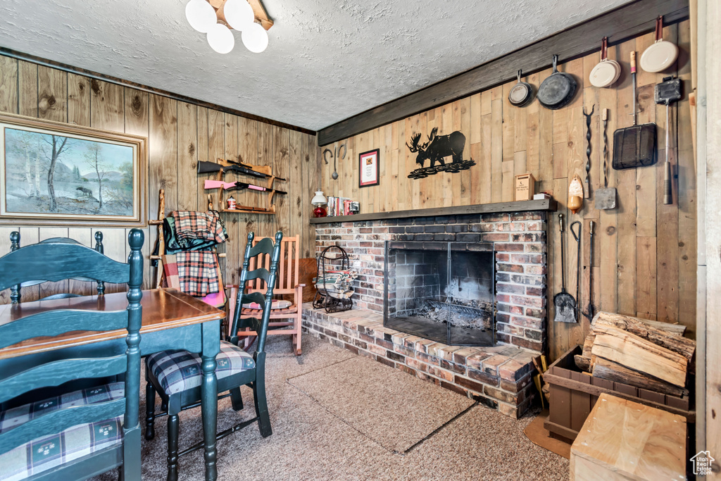 Carpeted living area featuring wood walls, a textured ceiling, and a brick fireplace