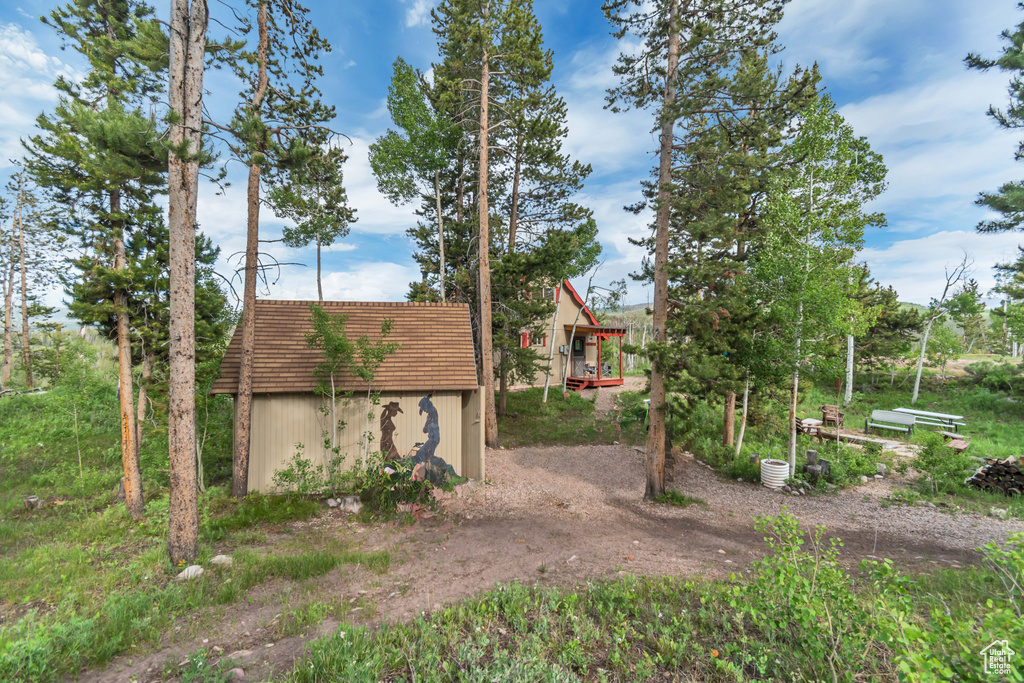 View of side of home featuring a storage shed and a tile roof