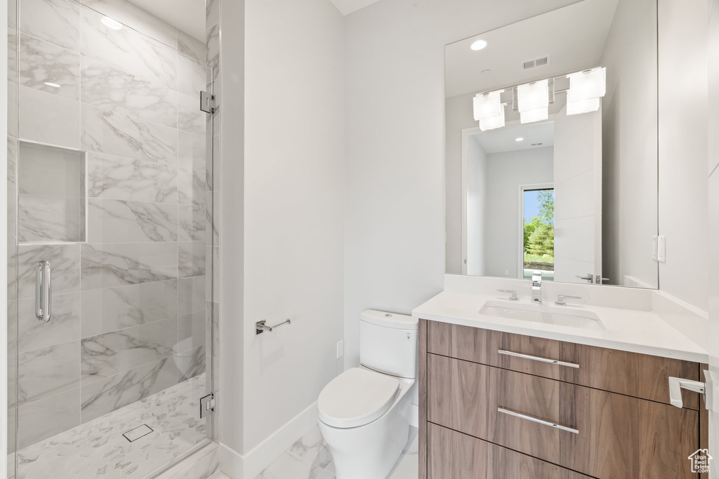 Full bath with marble look tiles, vanity, toilet, baseboards, and a shower stall
