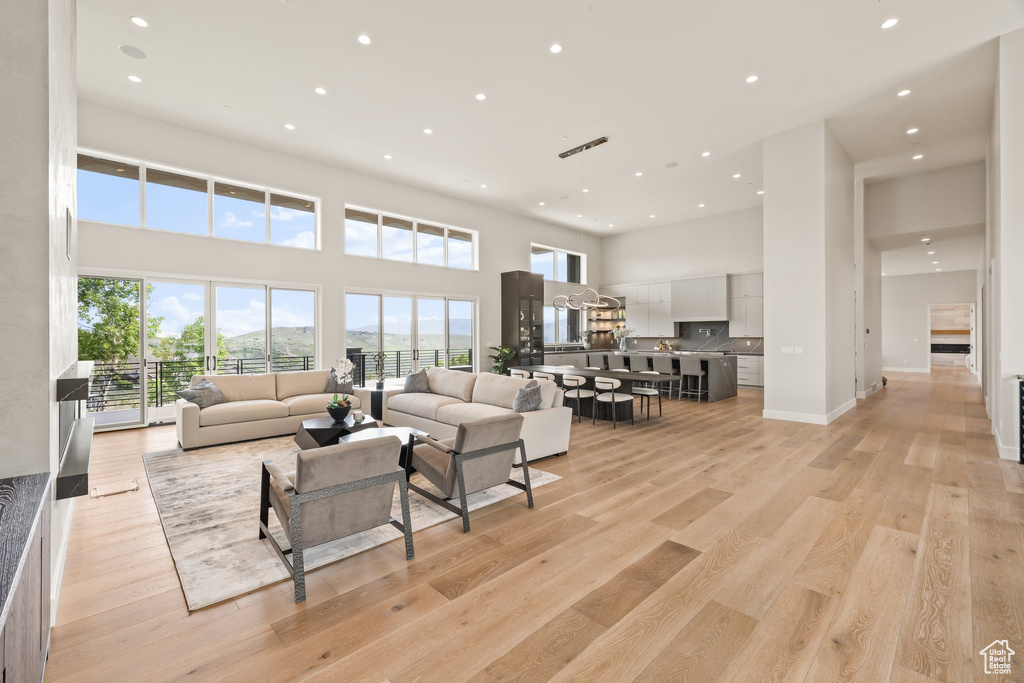 Living area with recessed lighting, a high ceiling, light wood-style flooring, and baseboards