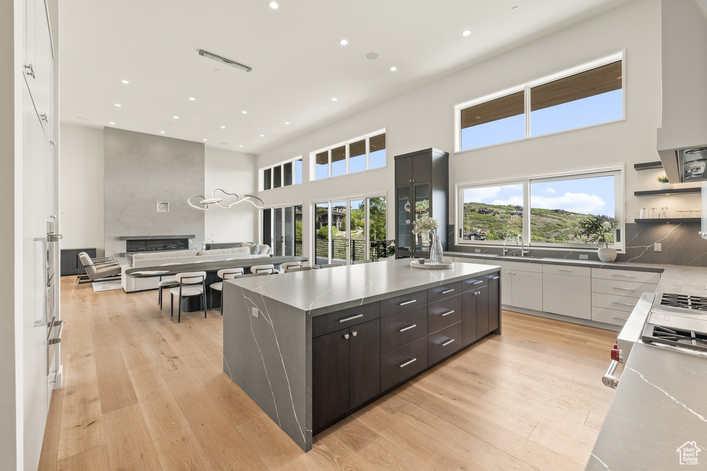 Kitchen featuring modern cabinets, a high ceiling, open floor plan, light wood-type flooring, and recessed lighting