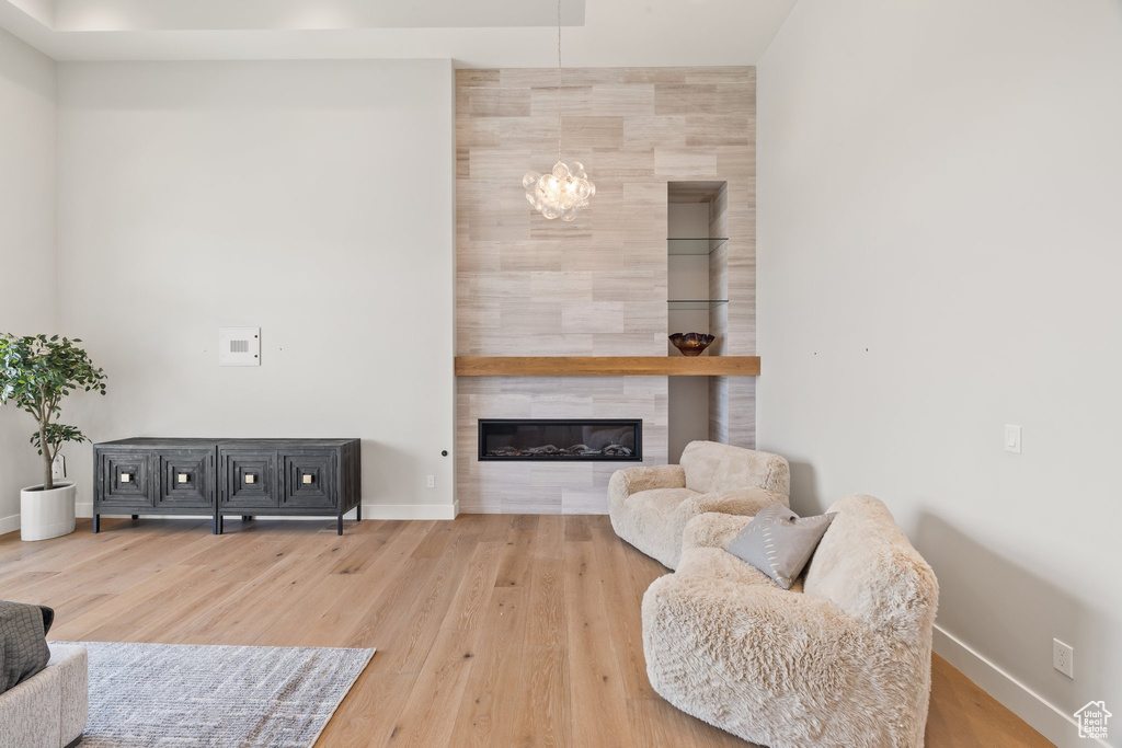 Living room featuring wood finished floors, baseboards, a chandelier, and a fireplace