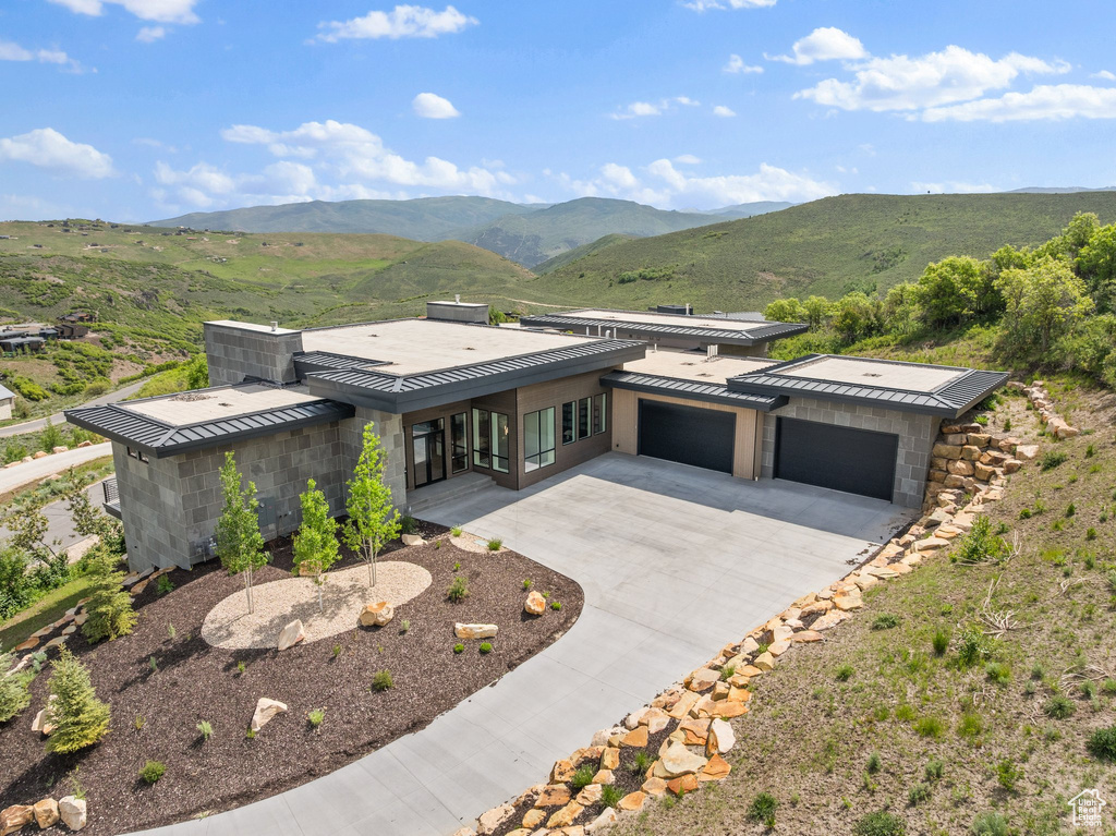 Contemporary home featuring a garage, driveway, metal roof, and a mountain view