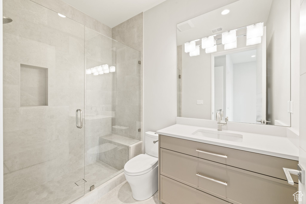 Bathroom featuring toilet, vanity, and a shower stall