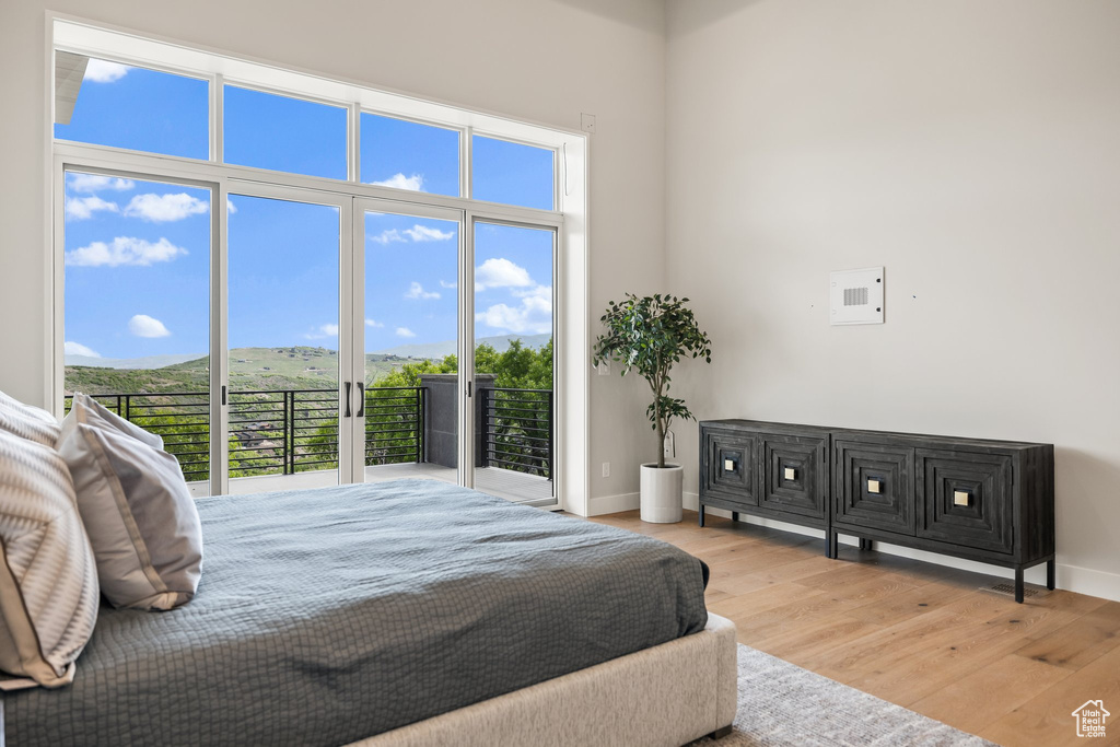 Bedroom featuring wood finished floors, multiple windows, baseboards, and a towering ceiling