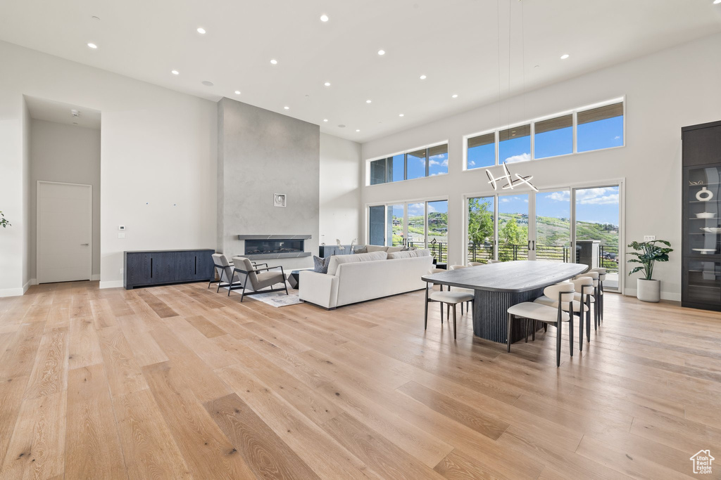 Dining room with a high ceiling, recessed lighting, light wood-style floors, a fireplace, and baseboards