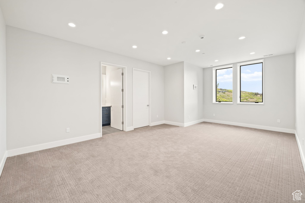 Spare room featuring recessed lighting, light carpet, and baseboards
