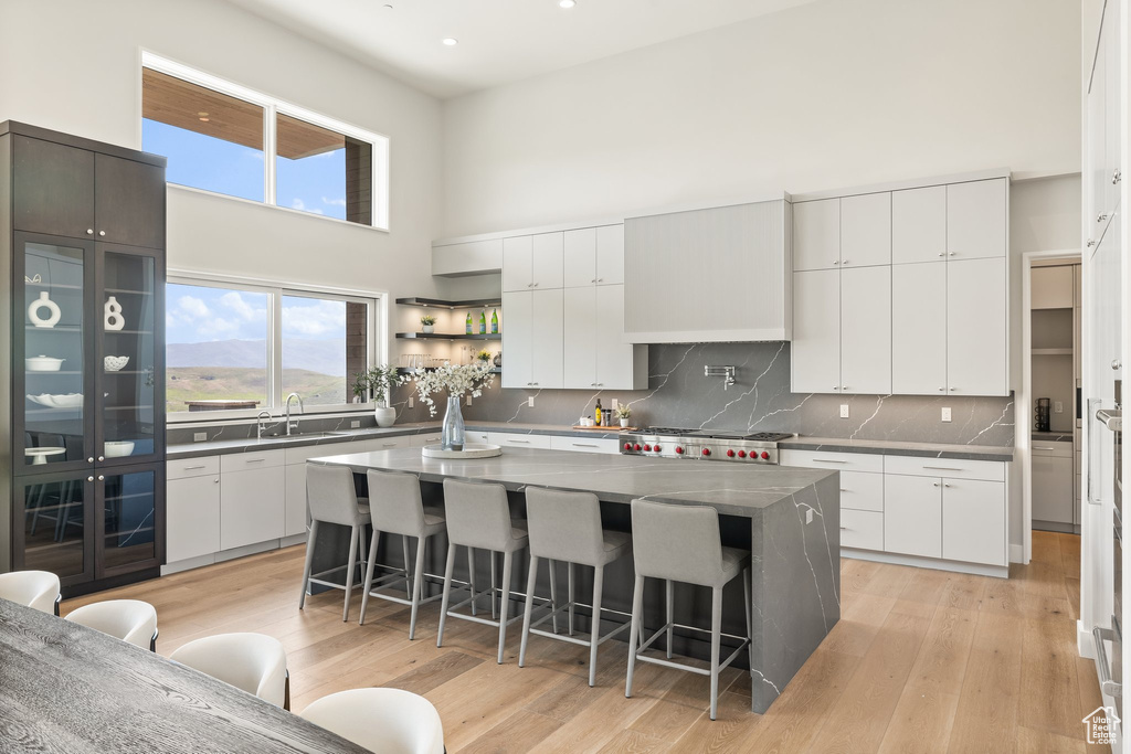 Kitchen with a breakfast bar area, a towering ceiling, decorative backsplash, a center island, and open shelves