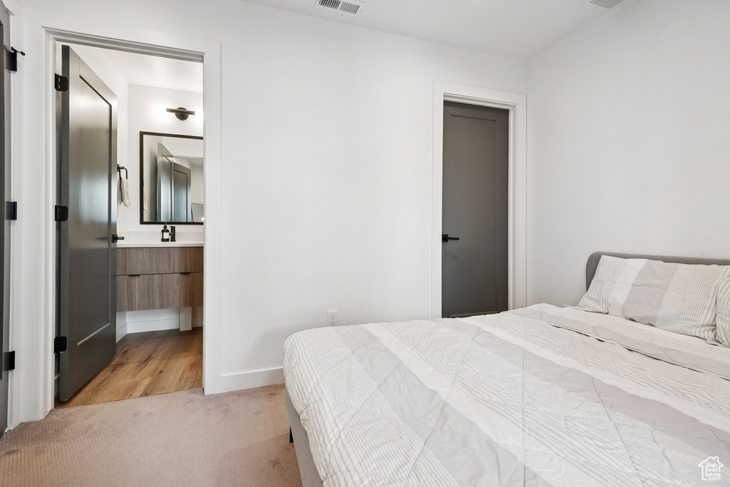 Bedroom with light carpet, a sink, and baseboards