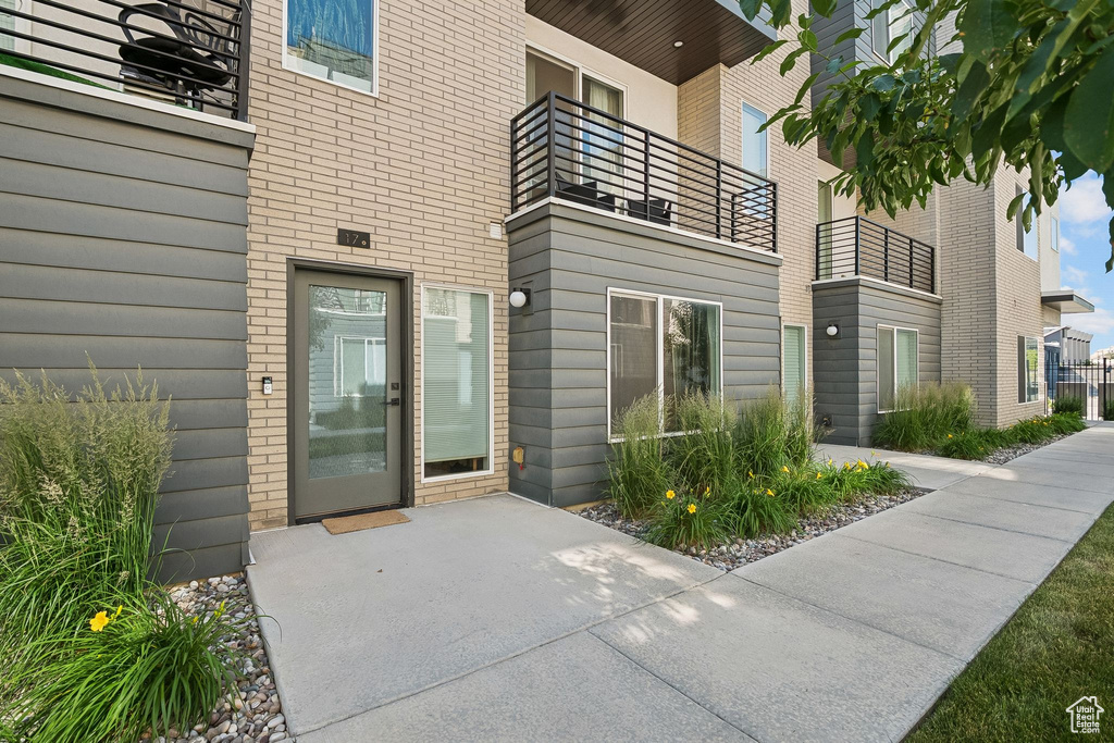 View of exterior entry with brick siding and a balcony