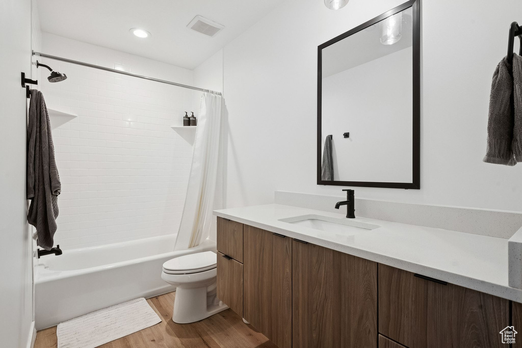Bathroom featuring vanity, wood finished floors, toilet, and shower / bath combo with shower curtain