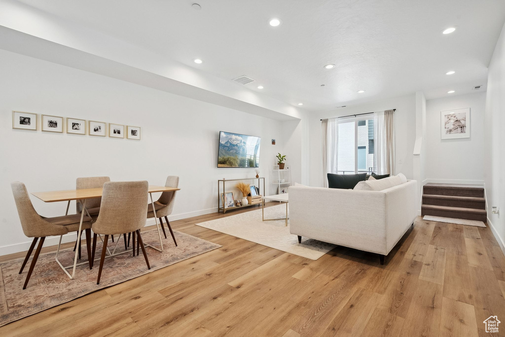 Dining space with light wood finished floors, recessed lighting, baseboards, and stairs