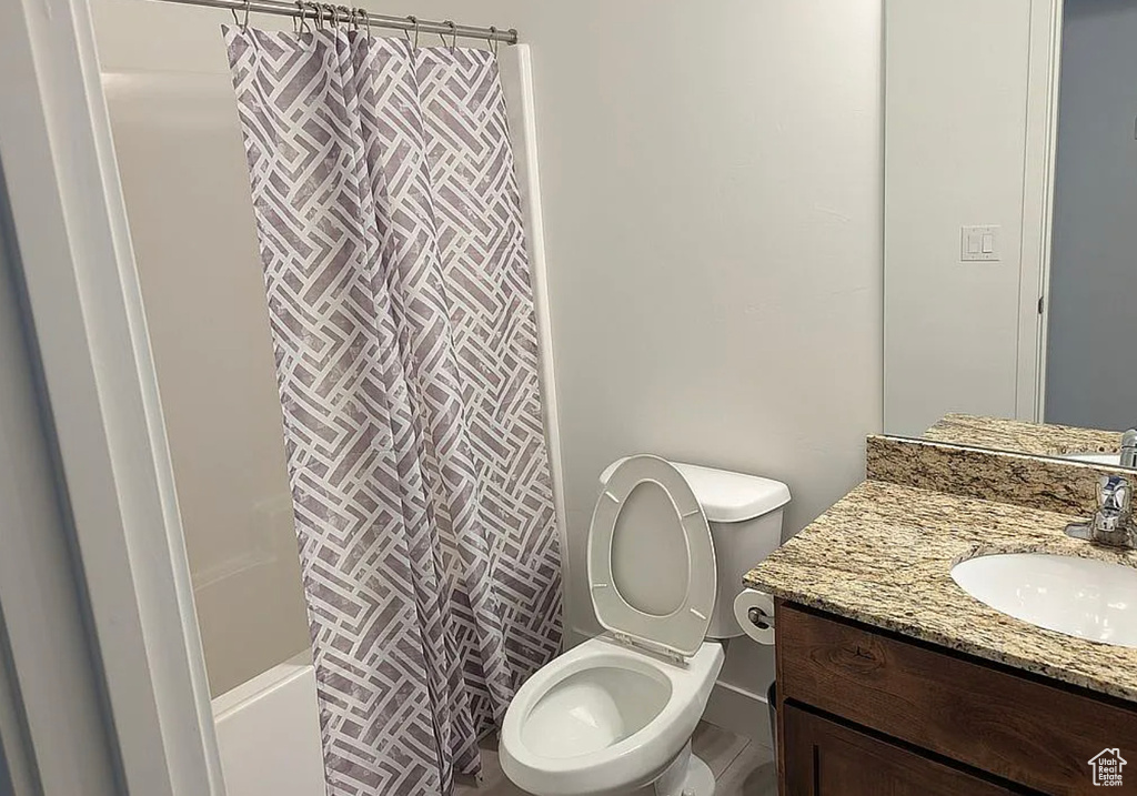 Bathroom featuring vanity, toilet, and shower / bath combination with curtain